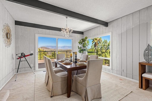 dining area with plenty of natural light, beam ceiling, a notable chandelier, a mountain view, and a textured ceiling