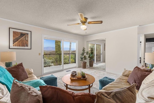 living room featuring ornamental molding, carpet flooring, ceiling fan, and a textured ceiling