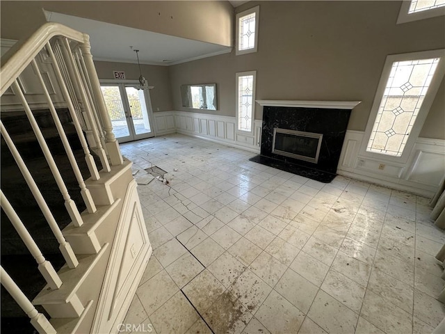 unfurnished living room with a premium fireplace, plenty of natural light, and crown molding