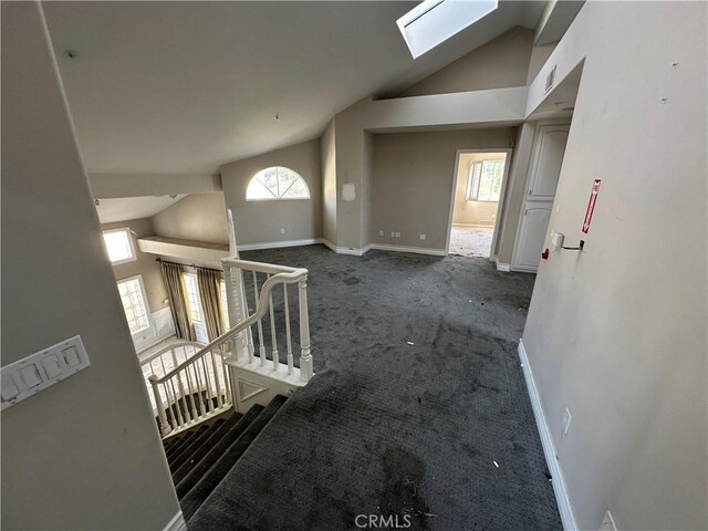 interior space with dark colored carpet, high vaulted ceiling, and a skylight