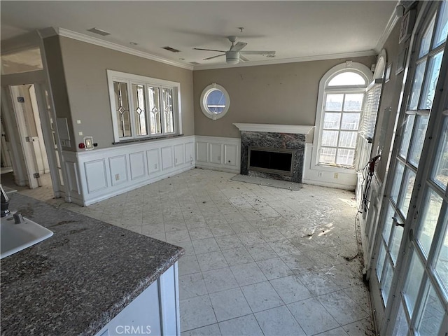 unfurnished living room featuring ornamental molding, sink, ceiling fan, and a fireplace