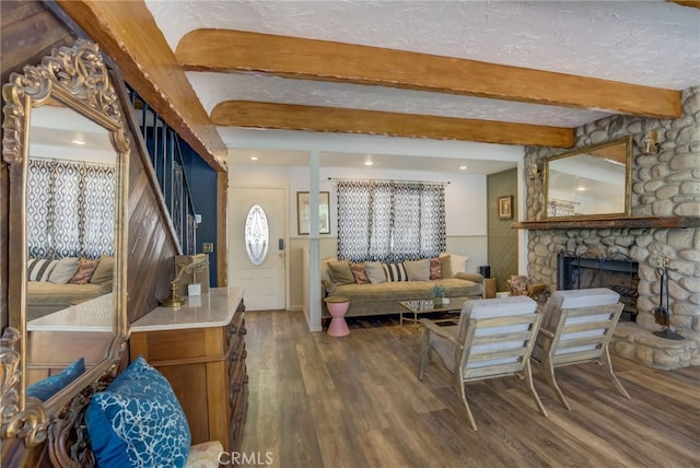 living room with beam ceiling, a stone fireplace, a textured ceiling, and dark hardwood / wood-style flooring