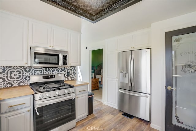 kitchen featuring backsplash, appliances with stainless steel finishes, light wood-type flooring, and white cabinets