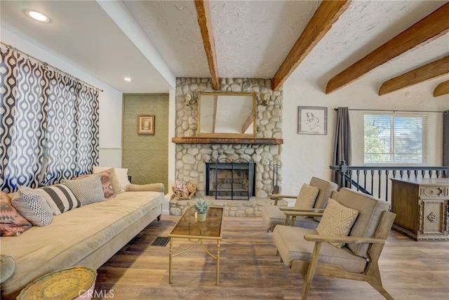 living room with beamed ceiling, a fireplace, hardwood / wood-style floors, and a textured ceiling