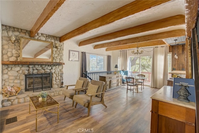 living room with a notable chandelier, hardwood / wood-style flooring, a fireplace, and a textured ceiling