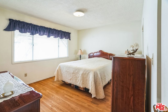 bedroom with a textured ceiling and light wood-type flooring