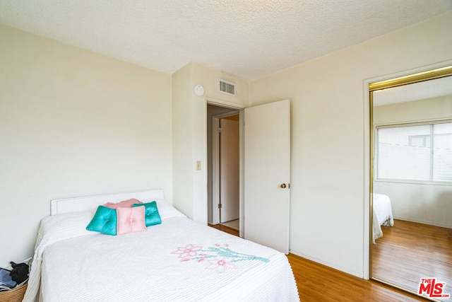 bedroom featuring hardwood / wood-style flooring and a textured ceiling