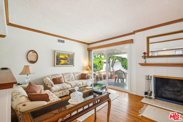 living room with hardwood / wood-style flooring, crown molding, a brick fireplace, and a textured ceiling