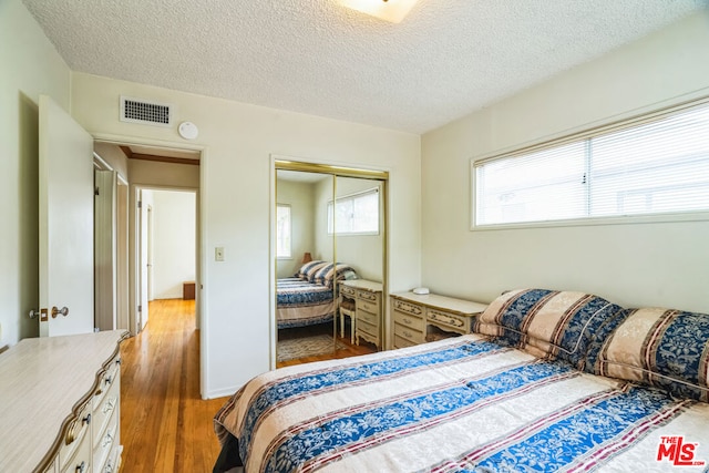 bedroom with wood-type flooring, a closet, and a textured ceiling