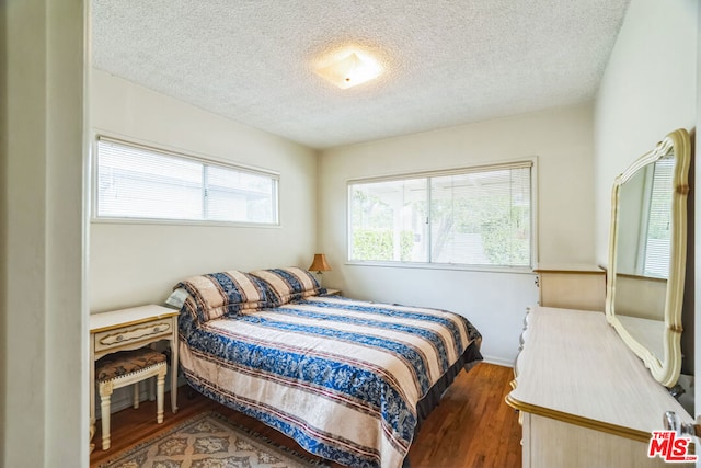 bedroom with dark wood-type flooring and a textured ceiling