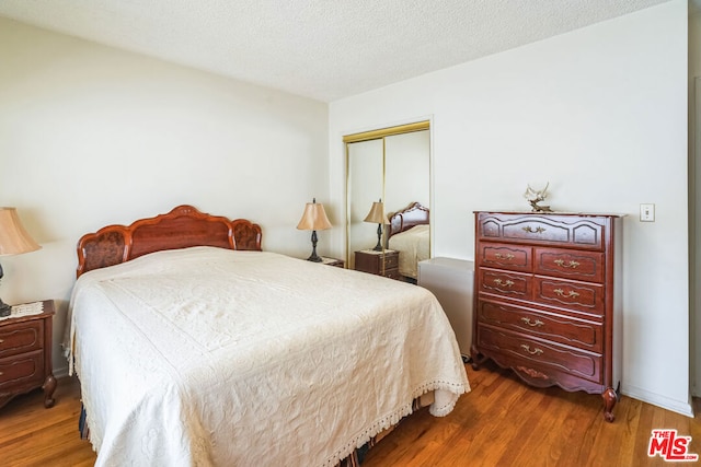 bedroom featuring hardwood / wood-style flooring, a closet, and a textured ceiling