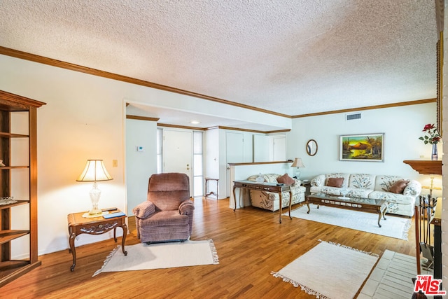 living room with hardwood / wood-style flooring, ornamental molding, and a textured ceiling