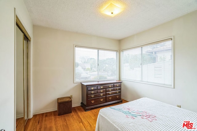 bedroom with light hardwood / wood-style flooring, a closet, and a textured ceiling