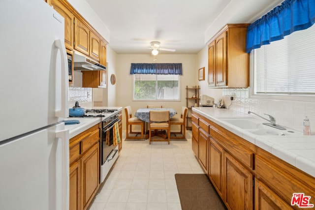 kitchen featuring sink, tasteful backsplash, tile countertops, ceiling fan, and white appliances