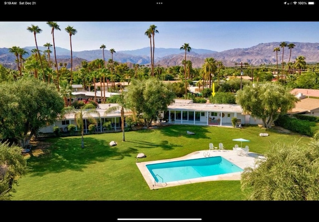 exterior space with a patio, a community pool, a mountain view, and a lawn