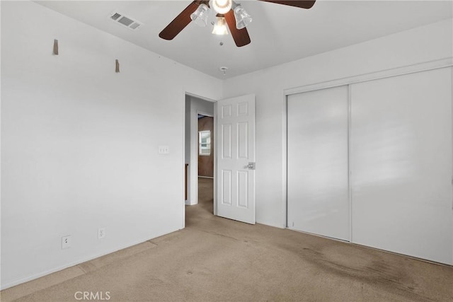 unfurnished bedroom with light carpet, ceiling fan, and a closet