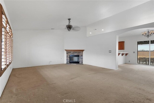 unfurnished living room with light colored carpet, a notable chandelier, and a fireplace