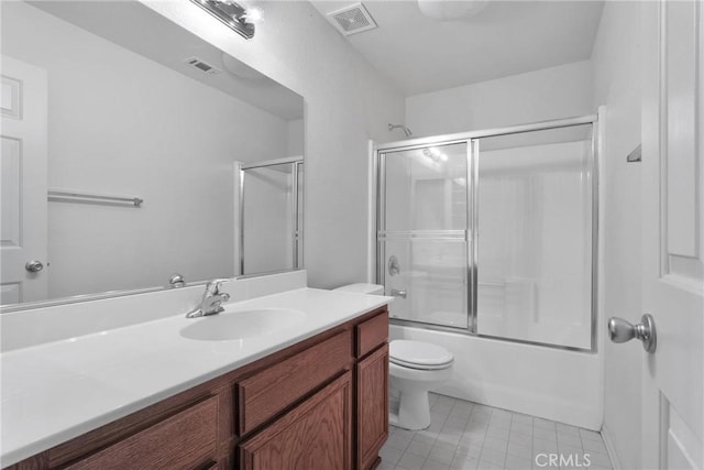 full bathroom with tile patterned flooring, vanity, combined bath / shower with glass door, and toilet