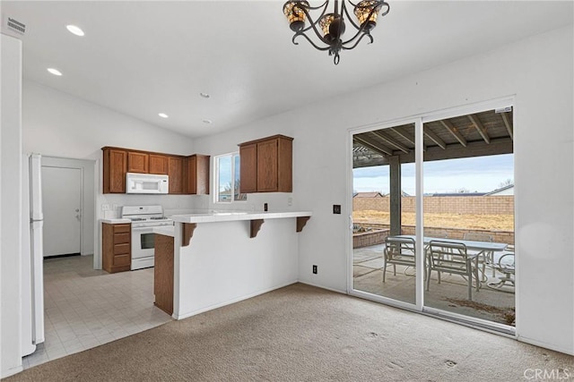 kitchen featuring white appliances, a kitchen bar, light colored carpet, kitchen peninsula, and a chandelier