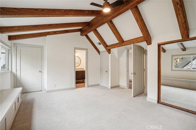 interior space with ceiling fan, lofted ceiling with beams, and light carpet