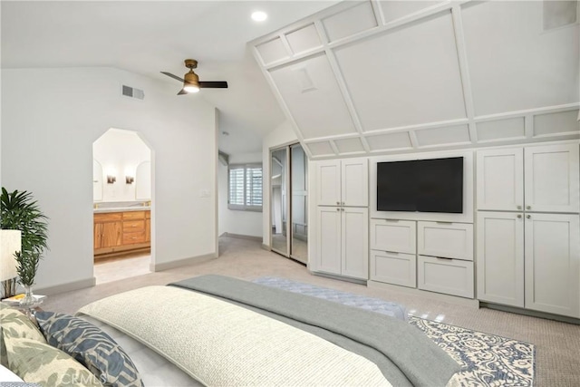 carpeted bedroom with ensuite bathroom, lofted ceiling, and ceiling fan