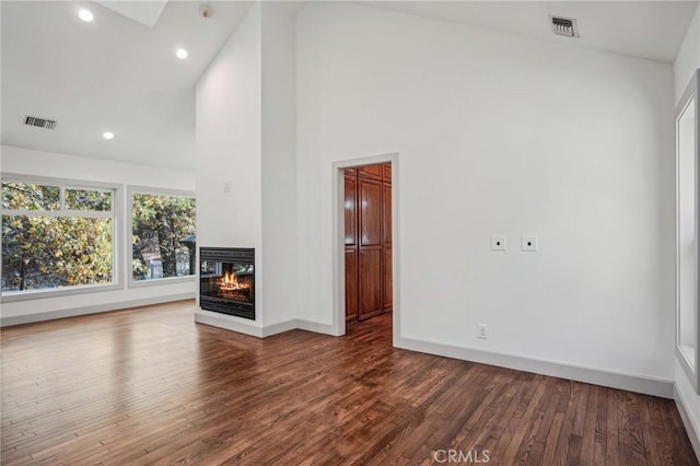 unfurnished living room featuring hardwood / wood-style flooring, a multi sided fireplace, and high vaulted ceiling