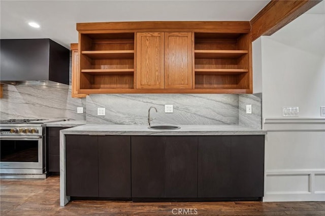 kitchen with sink, decorative backsplash, high end stainless steel range oven, dark wood-type flooring, and wall chimney exhaust hood