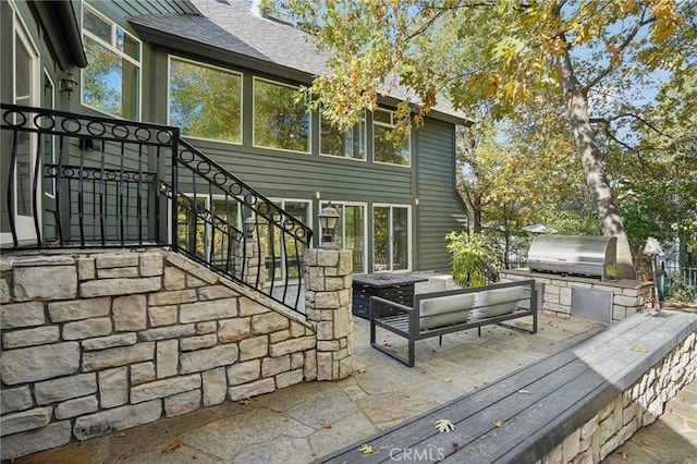 deck featuring area for grilling, a fire pit, a patio, and exterior kitchen