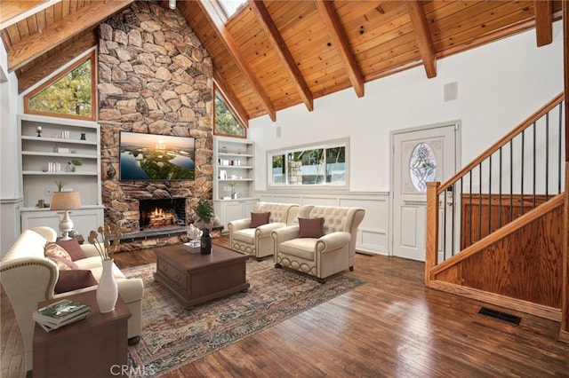 living room with beam ceiling, wood ceiling, dark wood-type flooring, and a stone fireplace