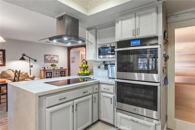 kitchen with tasteful backsplash, kitchen peninsula, island exhaust hood, black electric stovetop, and stainless steel double oven