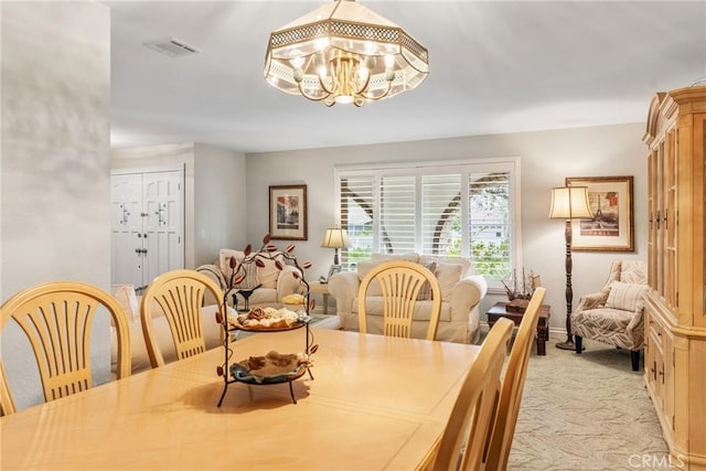 dining space with light colored carpet and a notable chandelier