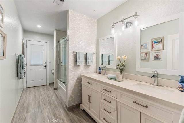 bathroom with bath / shower combo with glass door, wood-type flooring, and vanity