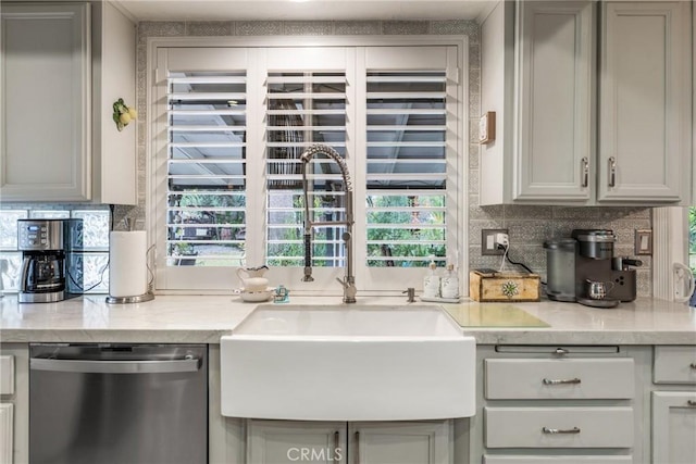 kitchen with tasteful backsplash, sink, light stone counters, and stainless steel dishwasher