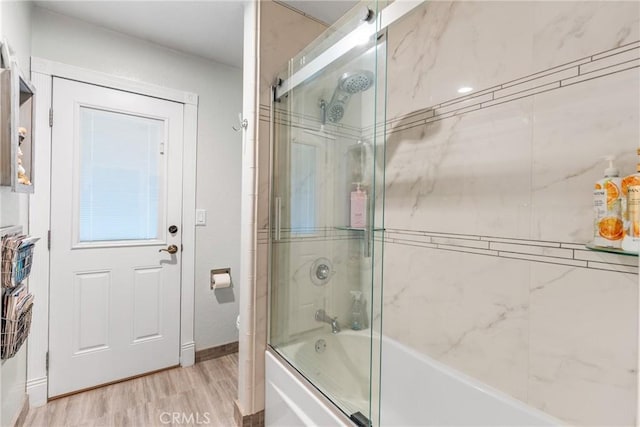 bathroom with hardwood / wood-style floors and combined bath / shower with glass door