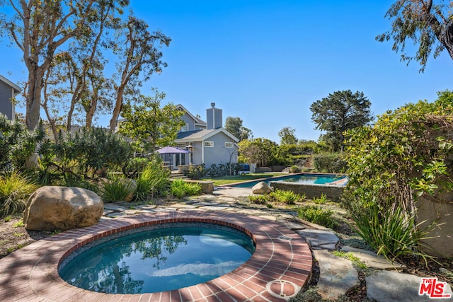 view of swimming pool with an in ground hot tub