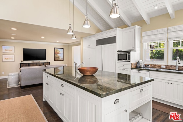 kitchen featuring sink, white cabinetry, built in appliances, lofted ceiling with beams, and a kitchen island