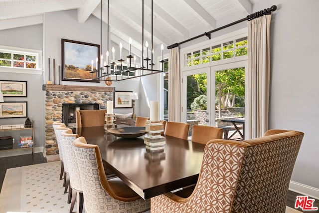 dining room featuring a stone fireplace, lofted ceiling with beams, and hardwood / wood-style flooring