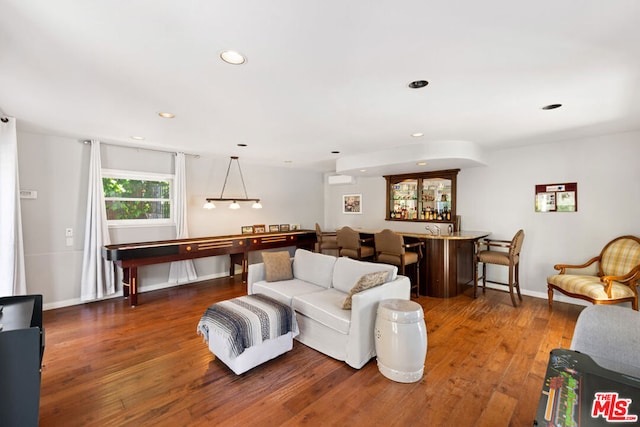 living room with dark wood-type flooring, a wall unit AC, and bar area