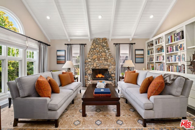 living room with a fireplace, a wealth of natural light, and lofted ceiling with beams