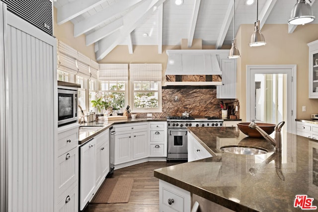 kitchen featuring vaulted ceiling with beams, white cabinets, dark stone counters, hanging light fixtures, and stainless steel appliances