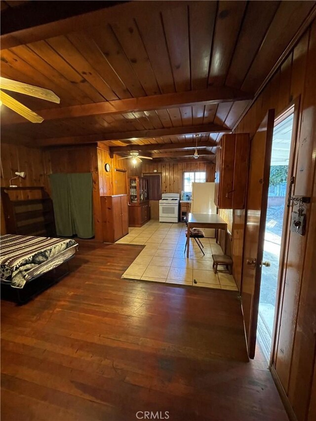 interior space with ceiling fan, white range with gas stovetop, wooden ceiling, and wooden walls