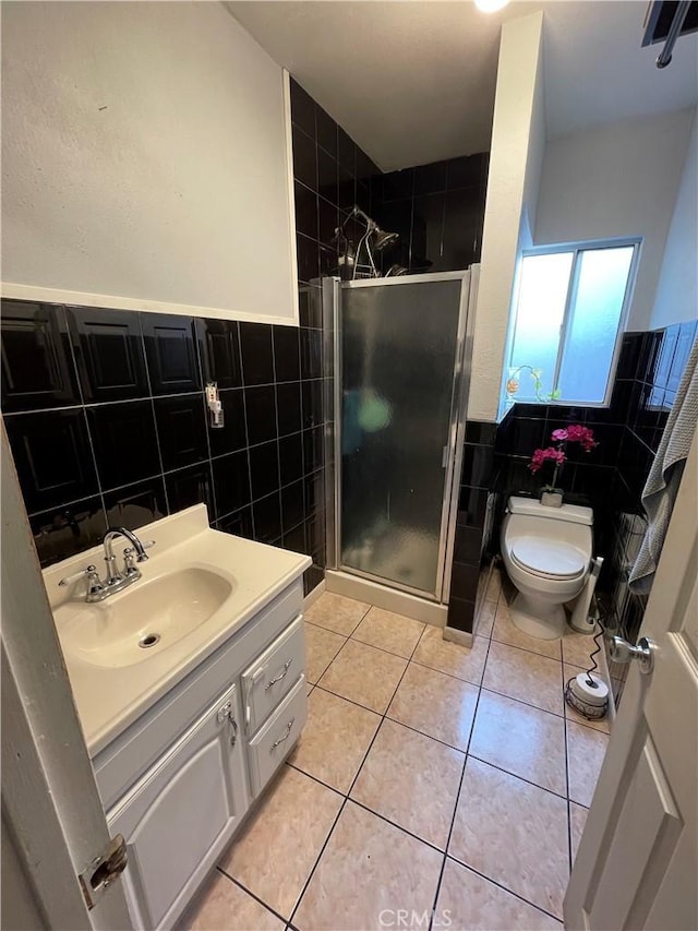 bathroom with vanity, a shower with door, tile patterned flooring, and tile walls