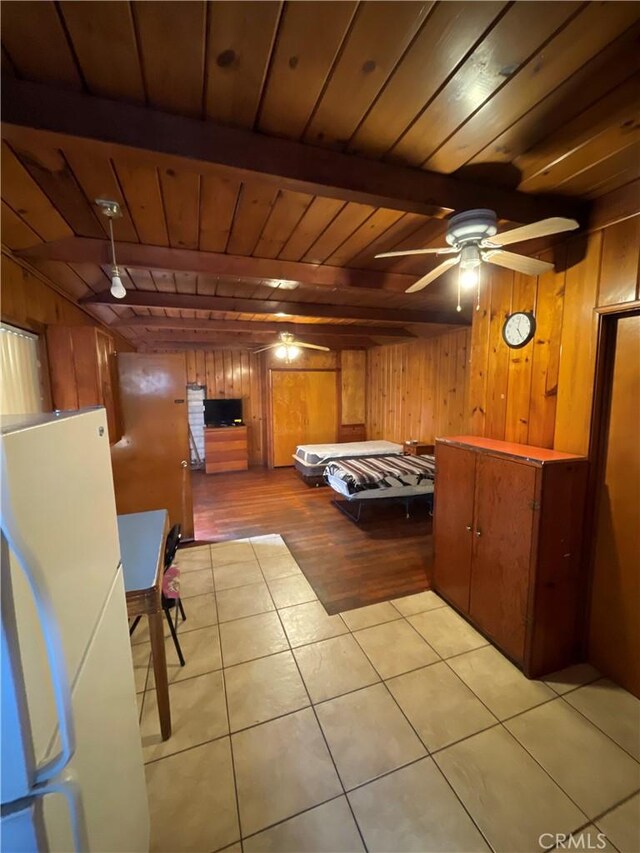 unfurnished bedroom featuring wooden walls, wooden ceiling, beamed ceiling, and white fridge