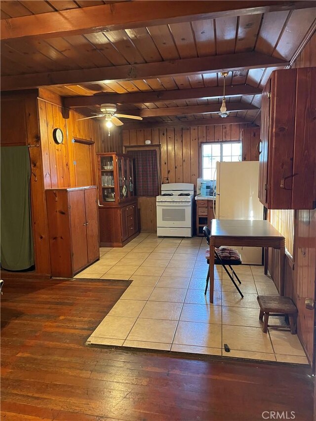 kitchen with beam ceiling, wood ceiling, white appliances, and wood walls