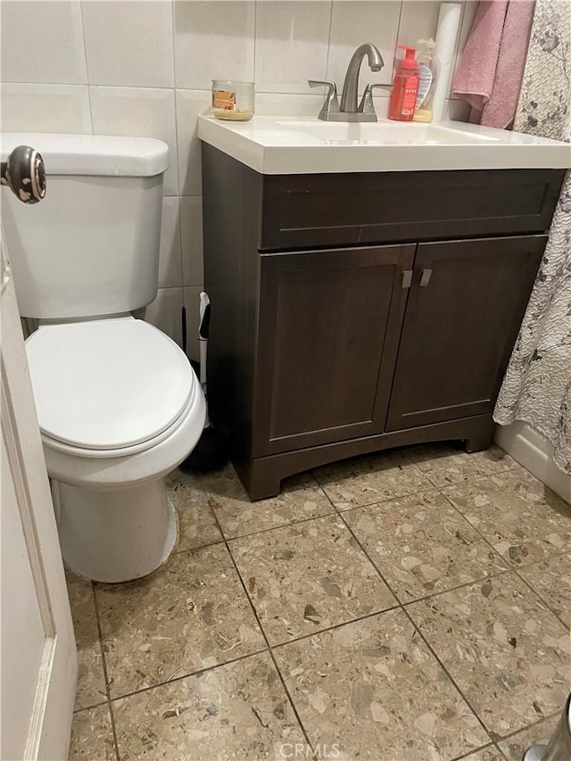 bathroom with vanity, tile walls, and toilet