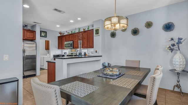 tiled dining room featuring separate washer and dryer, a notable chandelier, and sink