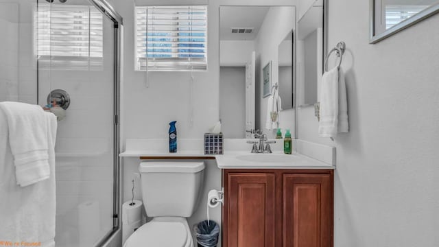 bathroom featuring vanity, a shower with shower door, toilet, and a healthy amount of sunlight