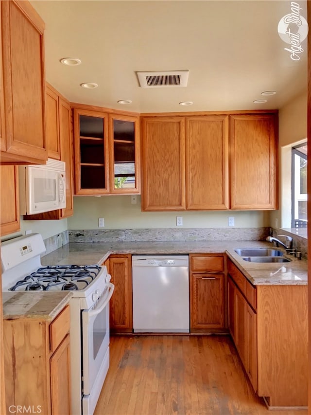 kitchen featuring white appliances, light hardwood / wood-style floors, and sink