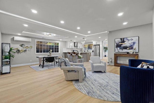 living room featuring an AC wall unit, a fireplace, and light hardwood / wood-style flooring