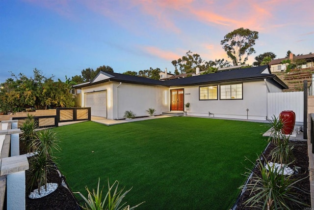 ranch-style home with a garage and a lawn